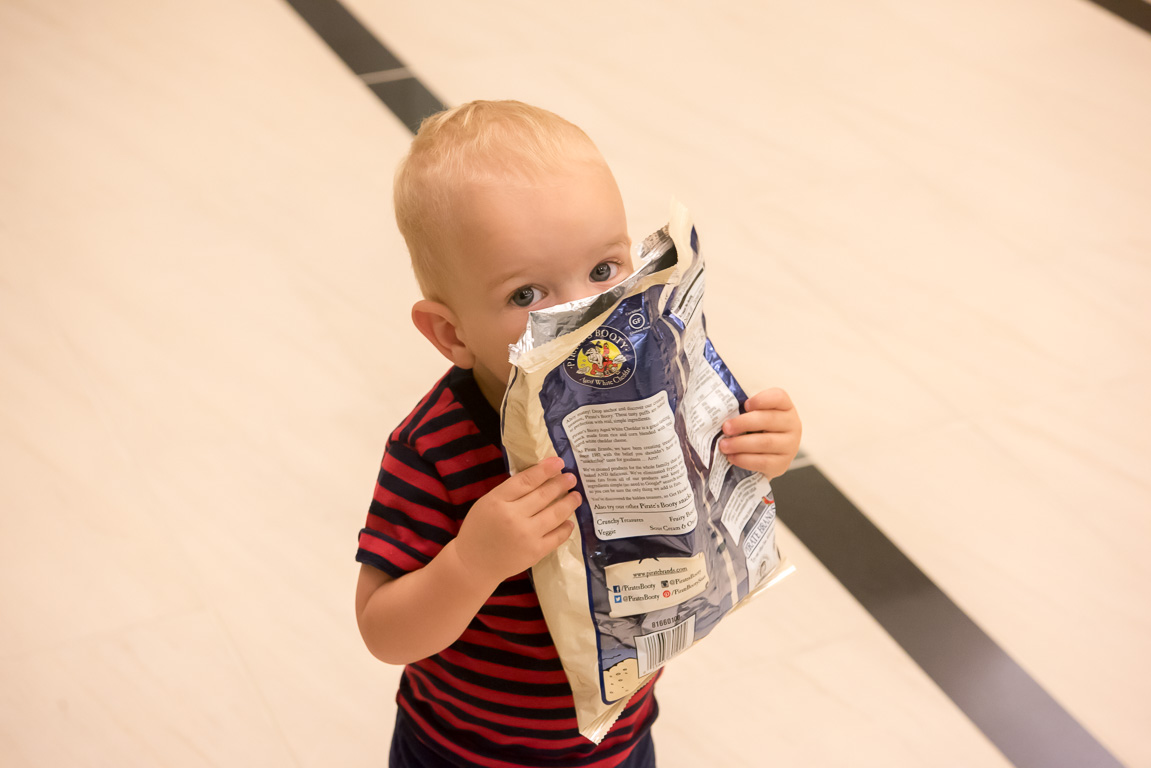 Riley peeking around a bag of chips